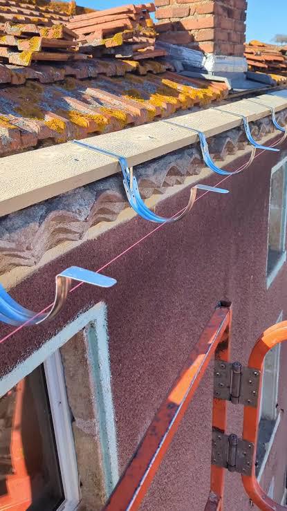 Crochets de gouttière alignés au cordeau sous une génoise
