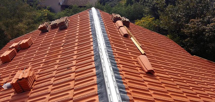 Faîtage ventilé en cours de pose sur un toit en tuiles mécaniques, faîtières empilées