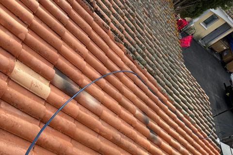 Toit en tuiles canal à moitié nettoyé, mousse d’un côté, tuiles propres de l’autre